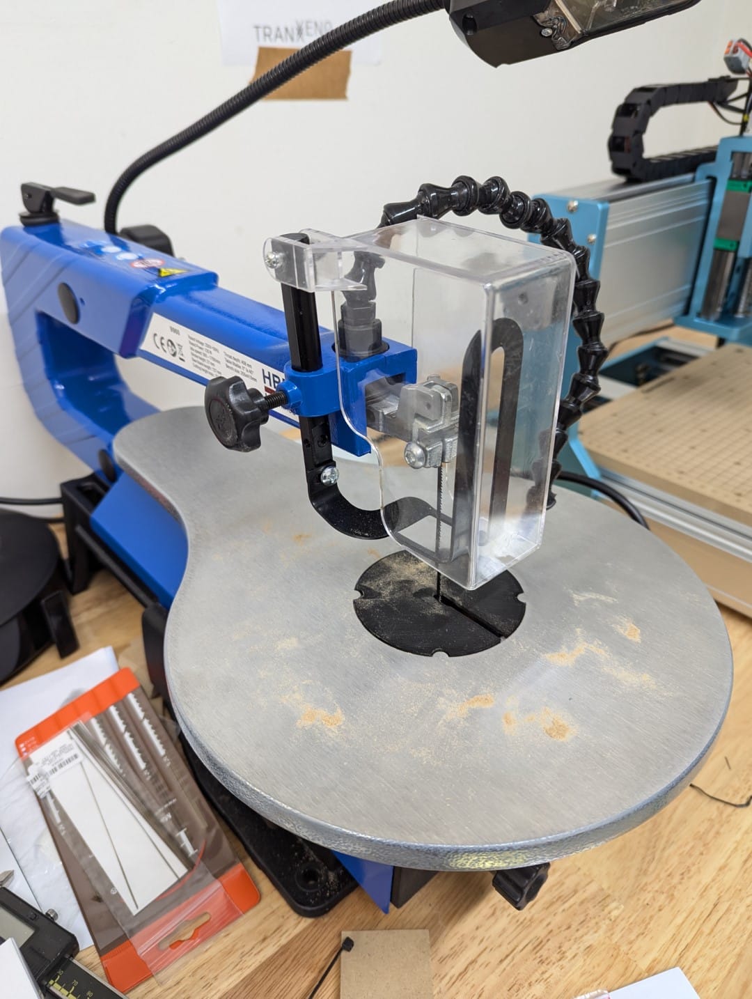 Scroll saw from HBM Machines, with blue and silver metal, and some sawdust from MDF.