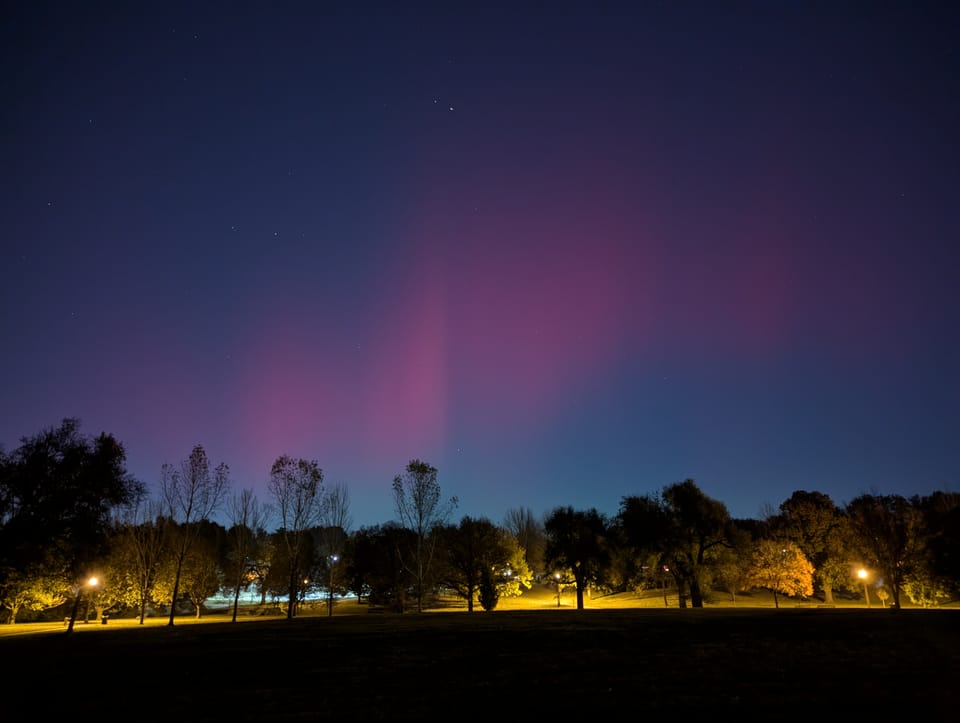 Reddish northern lights visible, somehow, from an urban area, and much further south than they should normally be visible.